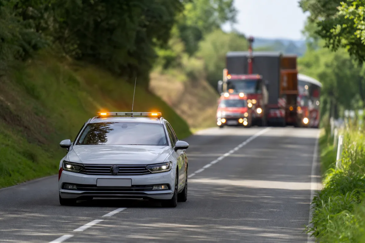 Voiture pilote équipée de feux jaunes ouvrant la route à un convoi exceptionnel
